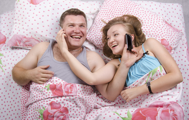 Young couple talking on the phone lying in bed - Photo, image