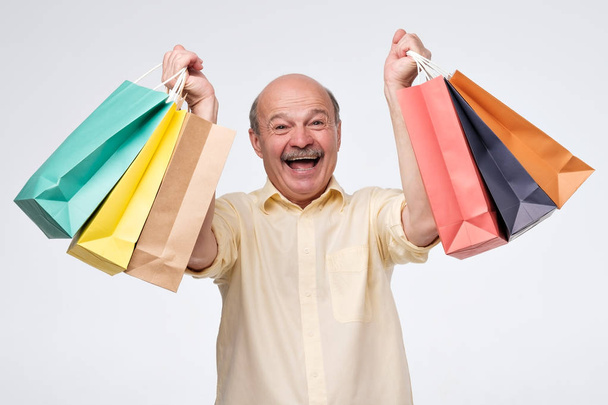 Счастливый зрелый латиноамериканец держит бумажные пакеты с подарками после покупки
. - Фото, изображение
