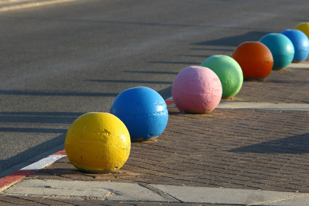 több színű beton golyók feküdjön a járdán a városban, és szolgál akadályt az úttest  - Fotó, kép