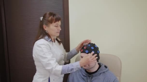 Lekarz stawia na mężczyznę zestaw słuchawkowy do badania ludzkiego mózgu. - Materiał filmowy, wideo