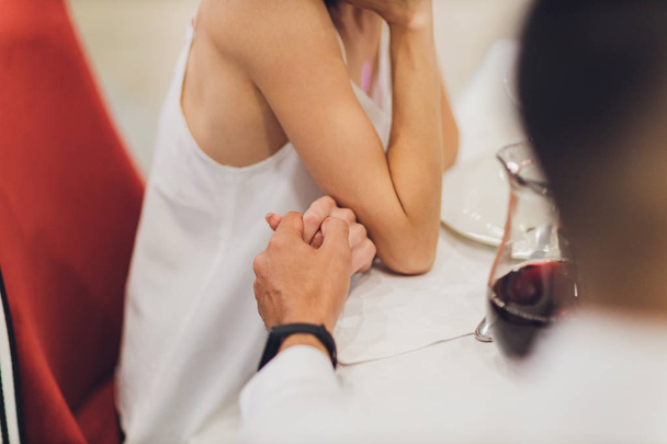 Man and woman at the restaurant, holding hands together. - Photo, Image
