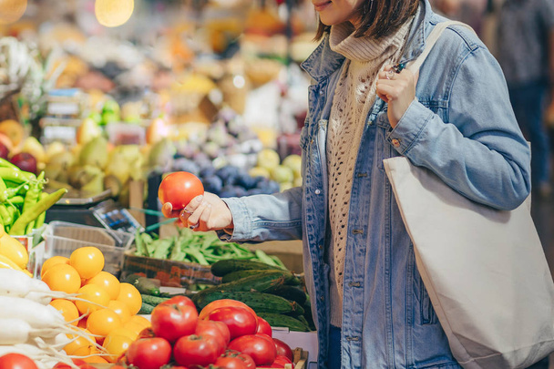 Woman is chooses fruits and vegetables at food market. Reusable eco bag for shopping. Sustainable lifestyle. Eco friendly concept.  - Foto, afbeelding