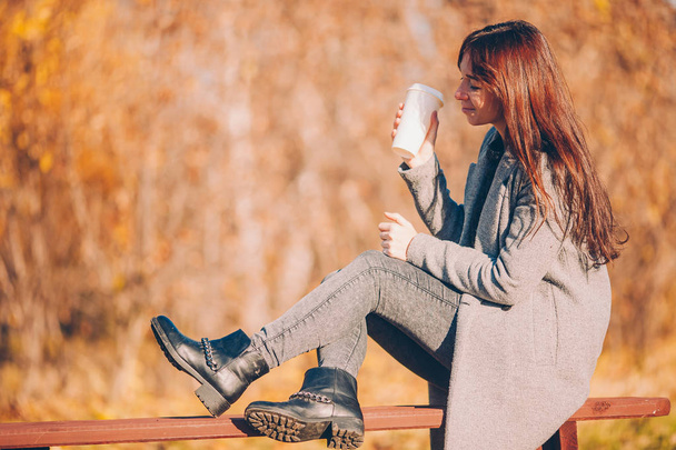 Concetto autunnale - bella donna che beve caffè nel parco autunnale sotto fogliame autunnale - Foto, immagini