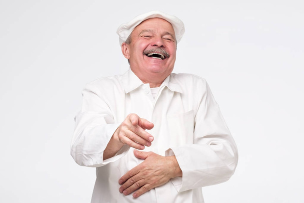 Tyytyväinen kypsä latino kokki kokki nauraa osoittaa sinua
. - Valokuva, kuva