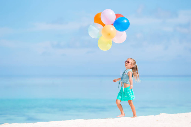 Schattig meisje spelen met ballonnen op het strand - Foto, afbeelding