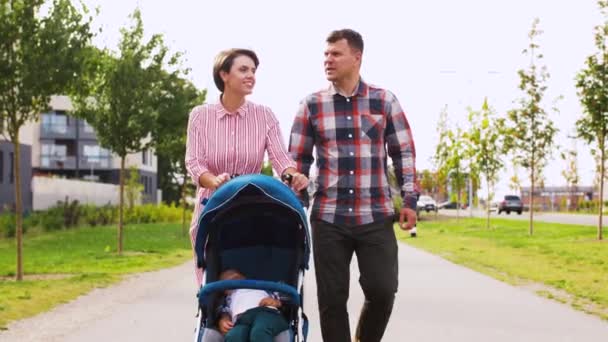 family with baby in stroller walking along city - Video
