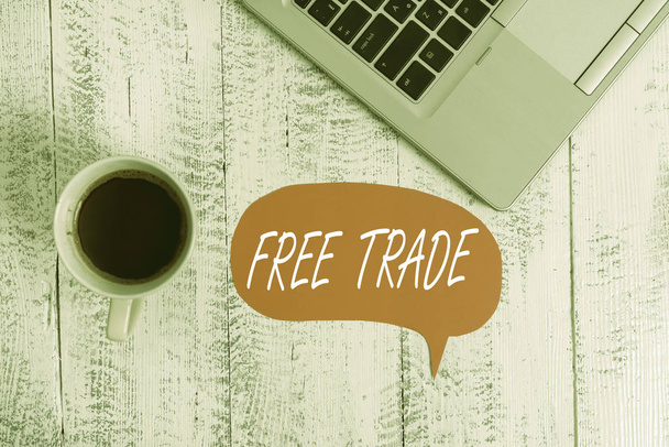 Word writing text Free Trade. Business concept for The ability to buy and sell on your own terms and means Trendy metallic open laptop speech bubble vintage wooden table coffee cup. - Photo, Image