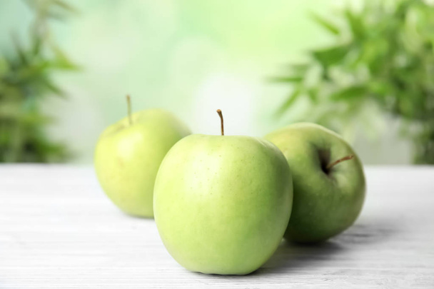 Fresh ripe green apples on white wooden table against blurred background, closeup view. Space for text - Valokuva, kuva
