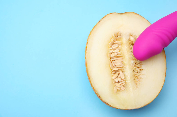 Half of melon and purple vibrator on blue background, flat lay with space for text. Sex concept - Foto, Imagen