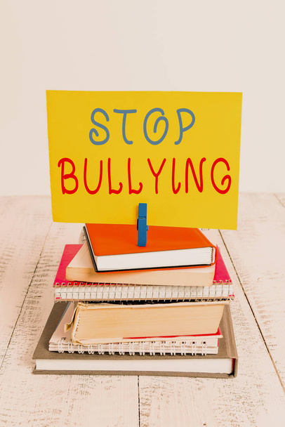 Conceptual hand writing showing Stop Bullying. Business photo showcasing Fight and Eliminate this Aggressive Unacceptable Behavior pile stacked books notebook pin color reminder white wooden. - Photo, Image