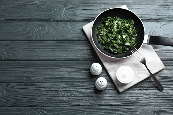 Tasty cooked spinach served on dark wooden table, flat lay with space for text. Healthy food - Photo, image