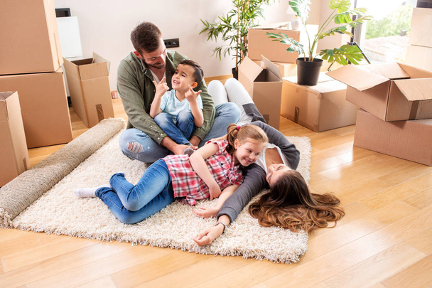 Happy family sitting on the floor of their new apartment  - Foto, Imagen