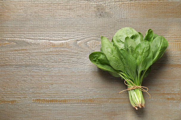 Bunch of fresh green healthy spinach on wooden table, top view. Space for text - Foto, imagen