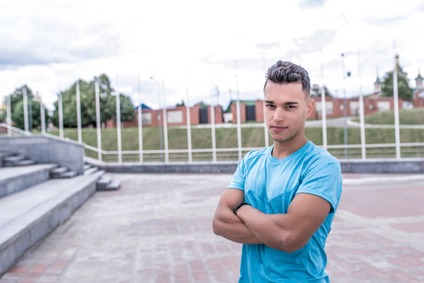 Athlete man smiles, looks carefully, close-up, serious look of trainer, summer in city, sports shirt, motivation youth lifestyle, outdoor training. Motivation active lifestyle. Free space for text. - Fotoğraf, Görsel
