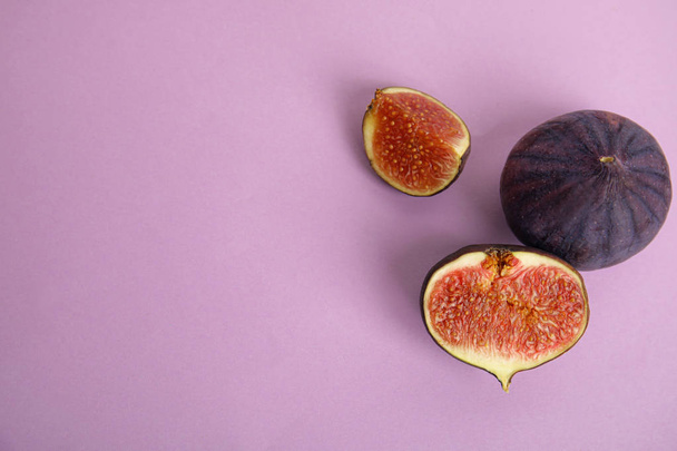Tasty fresh fig fruits on violet background, flat lay. Space for text - Foto, Bild