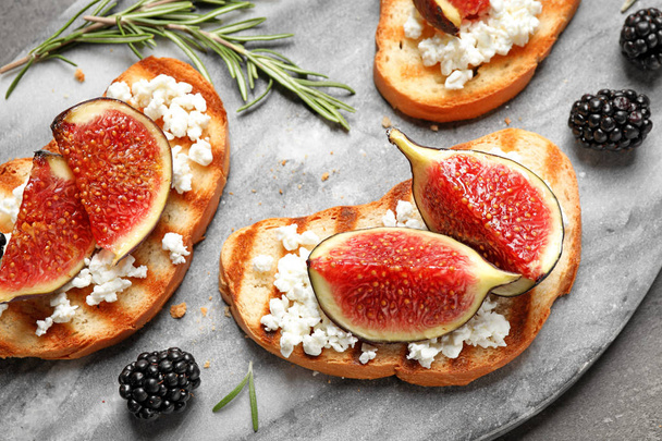 Bruschettas with ripe figs and cheese served on board, closeup - 写真・画像