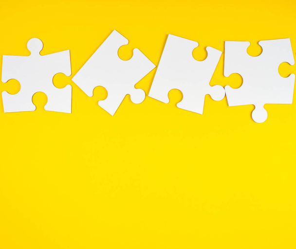 blank white big puzzles on yellow background - Фото, изображение