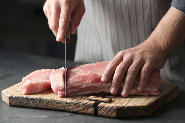 Man cutting fresh raw meat on table, closeup - 写真・画像
