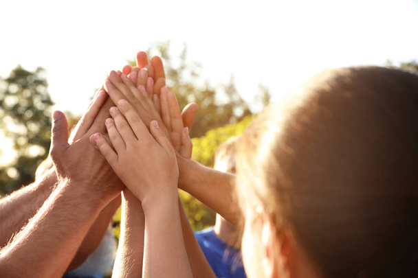Gruppo di volontari che si uniscono le mani all'aperto nella giornata di sole
 - Foto, immagini
