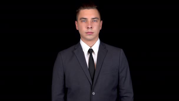 Young businessman shows like on hand. Man in a black suit on a black background - Footage, Video