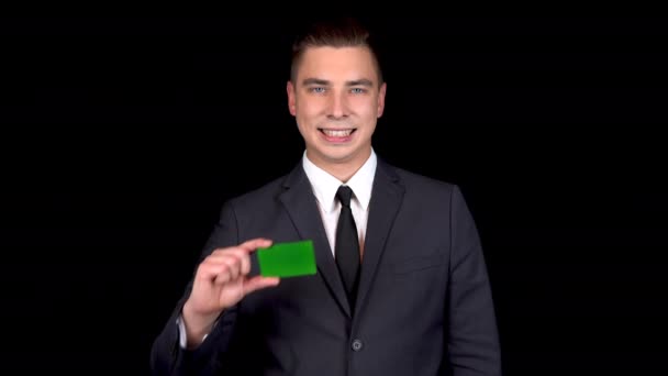 Genç işadamı yeşil bir kart sunar ve eliyle gösterir. Kromakey yeşil kart. - Video, Çekim