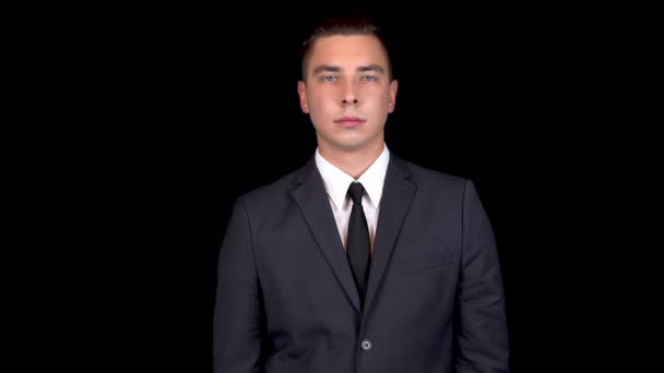 Young businessman shakes his head denying. Man in a black suit on a black background - Footage, Video