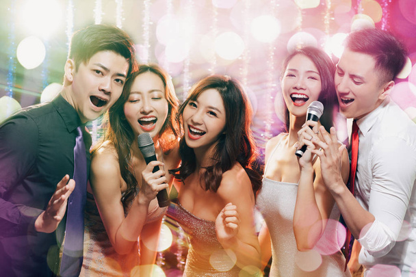 mladá skupina držící mikrofon a zpěv v karaoke - Fotografie, Obrázek