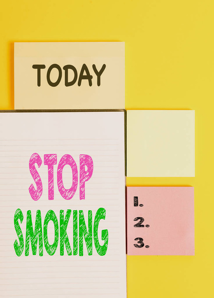 単語の書き込みテキスト喫煙を停止します。タバコ中毒の使用を中止または中止するためのビジネスコンセプト 黄色の背景テーブルにコピースペースを持つ空の紙を色付け. - 写真・画像