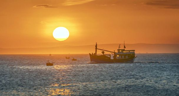 Paysage marin au coucher du soleil lorsque les bateaux de pêche sur la mer pour récolter du poisson fin de la journée
. - Photo, image