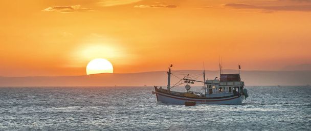魚を収穫するために漁船が海に出るとき、日没時の海の風景は一日を終えます. - 写真・画像