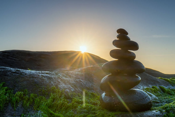 Stacked Pebbles art on mossy rocks welcomes beautiful new day - Photo, Image