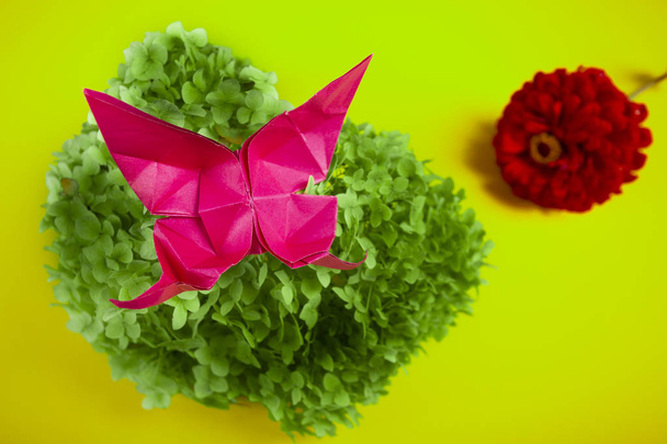 Origami-Schmetterling auf einem grünen Strauch in einem Korb auf einem farbigen Hintergrund schönen Strauß Studio Nahaufnahme auf Grasgrün - Foto, Bild