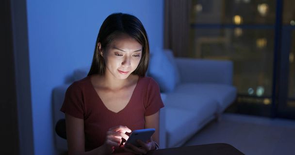 Mulher uso de telefone celular em casa à noite
 - Foto, Imagem