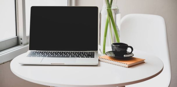 Minimális munkahely nyitott laptoppal, kávéscsésze és irodai kellékek a kényelmes sarokban  - Fotó, kép