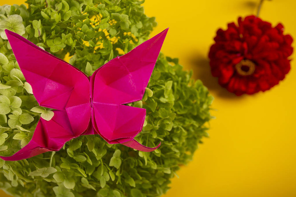Origami handgemaakte vervaardigde Butterfly op een groene Bush in een mand op een gekleurde achtergrond mooie boeket Studio close shot - Foto, afbeelding