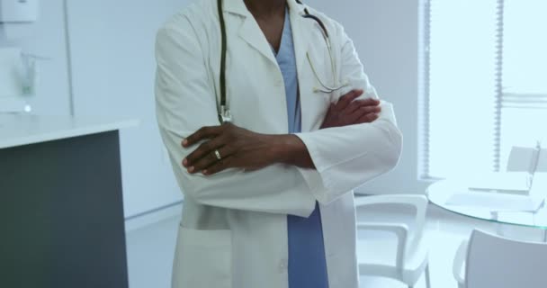 Front view of African american male doctor standing with arm crossed in the hospital. He is smiling and looking at camera, video - Felvétel, videó