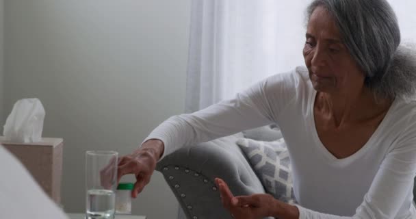 Front view close up of a mature mixed race woman undoing a bottle and taking a pill - Footage, Video