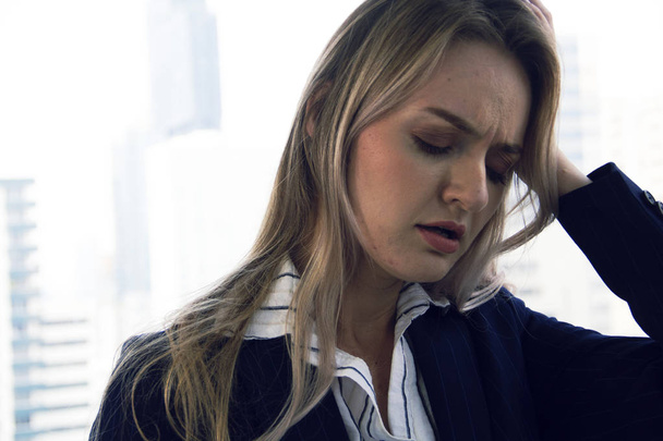 Close-up beautiful business woman sadness and hand on head in office and building background. - Photo, Image