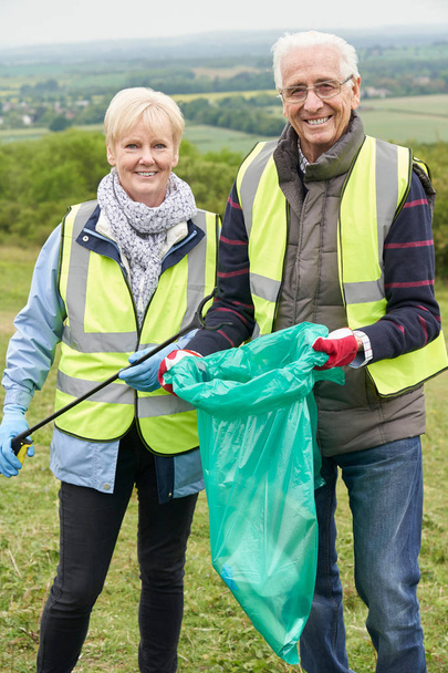 Portrait Of Helpful Senior Couple Collecting Litter In Countrysi - Фото, зображення