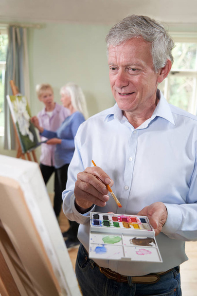 Senior Man Attending Painting Class With Teacher In Background   - Foto, Imagen