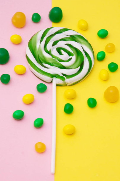 lollipop and candies on yellow and pink background - Foto, afbeelding