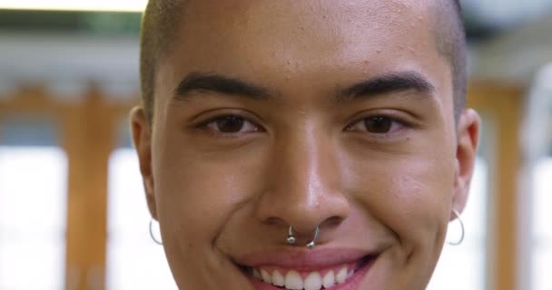 Portrait close up of a young mixed race male creative smiling to camera in a modern office - Záběry, video