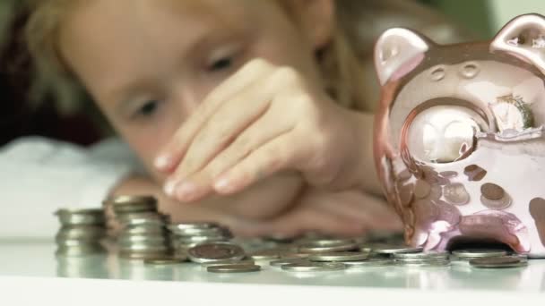 Niña preescolar pone dinero en una alcancía de cerdo rosa
 - Imágenes, Vídeo