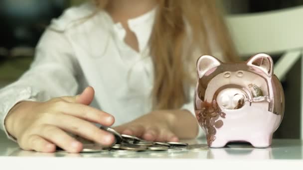 Girl preschooler puts money in a piggy bank pink pig - Footage, Video