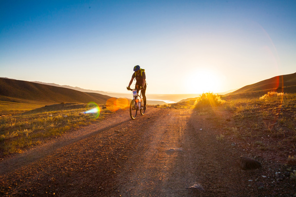 menina em uma bicicleta nos raios do sol nascente
 - Foto, Imagem