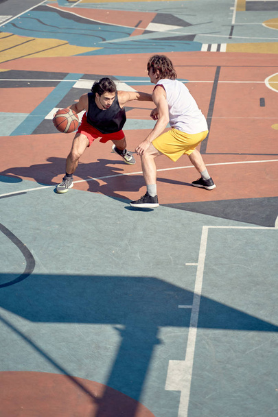 Top view image of two young sportsmen playing basketball on playground in morning. - 写真・画像