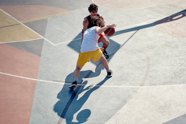 Top view of two athletes men playing basketball on playground in morning. - Valokuva, kuva
