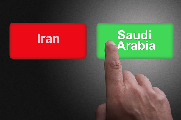 Buttons with written Saudi Arabia and Iran and pointing finger, on a gray gradient background: Concept of choosing Saudi Arabia - Photo, Image