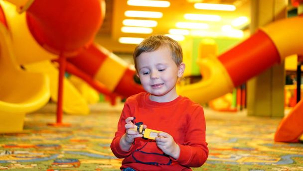 Aranyos kisfiú gyerek játszik egyedül színes műanyag oktató játék . - Fotó, kép