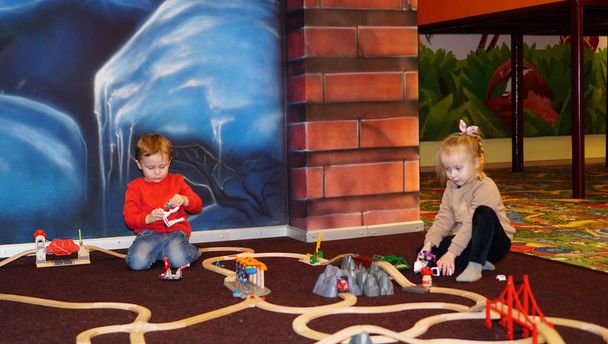 Χαριτωμένο μικρό αγόρι και κορίτσι που παίζουν μαζί με το πλαστικό εκπαιδευτικό παιχνίδι τρένο . - Φωτογραφία, εικόνα